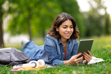 Beautiful Young Arab Woman Relaxing With Digital Tablet On Lawn In Park