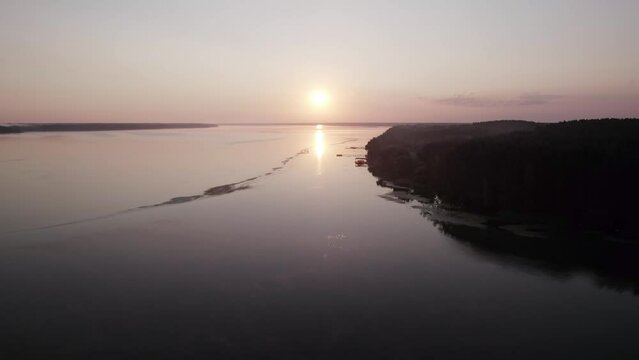 Drone flight ove a river directly to the sunrise