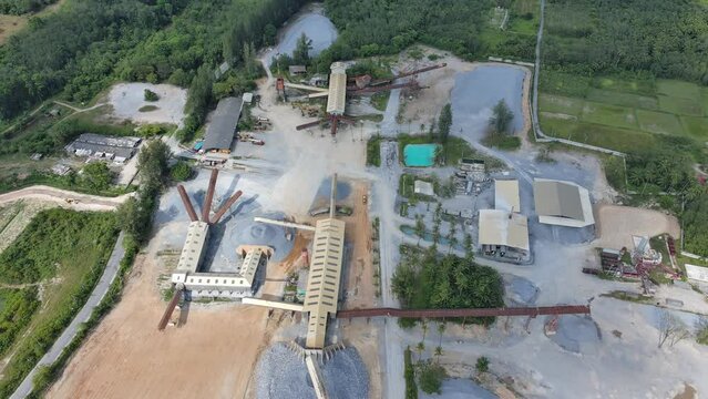 4k aerial view of stone factory with working gravel crushe and heavy construction machine equipment in quarry, rock industry business work for manufacture gravel, dust pollution to dirty environment