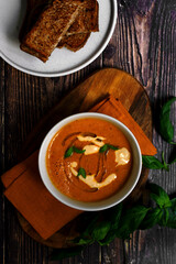 Tomato soup with cheesy bread. Wooden background. 