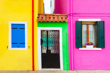 Fototapeta na wymiar Yellow and pink painted facades of the houses and windows with colorful shutters.