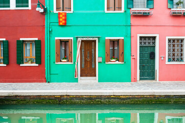Green and red houses on the canal in Burano island, Venice, Italy.