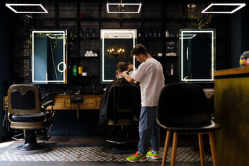 Style barbershop background. Casual attired hairdresser cutting hair of a client