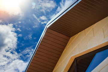 New roof with ridge, gable and cornice against the sky. Part of the attic window on the facade.