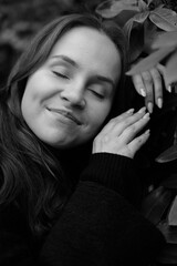 Brunette girl with closed eyes on the background of plantleaves