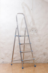 A simple stepladder stands on the floor in an empty home room.