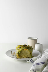 Pistachio spreadable cream cinnamon roll on a white plate. White background.