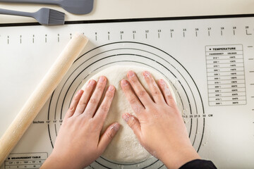 Kneading the dough on a silicone baking mat with round markings of different diameters to obtain a...