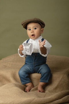 Cute funny baby dressed up like a newsboy holding a newspaper 