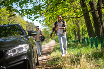 Obraz premium Young men stopping the car on the forest road