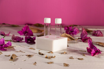 Frascos de vidrio transprente, pequeños, con tapa blanca, sin marca con flor de bugambilia y hojas secas, con fondo rosa