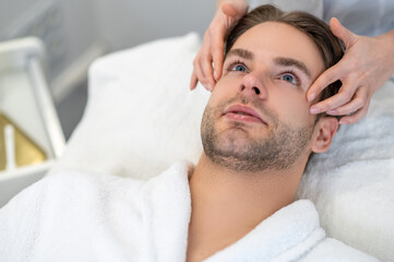 Young male client having face massage in a professional salon