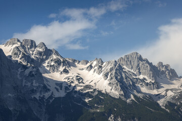 stunning high grey mountain with snow fields on a sunny day and blue sky, alpine area	