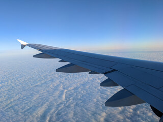 airplane wing during a flight, golden sunset sky and clouds	
