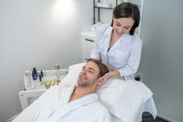 Dark-haired professional doing face massage to a male customer