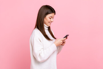 Side view of portrait optimistic girl using smartphone with happy expression, hearing pleasant...
