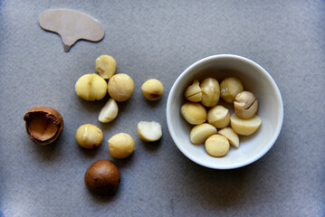 Delicious peeled Macadamia nut in a salad bowl on a gray background. The kernels of a delicious Macadamia nut close-up.