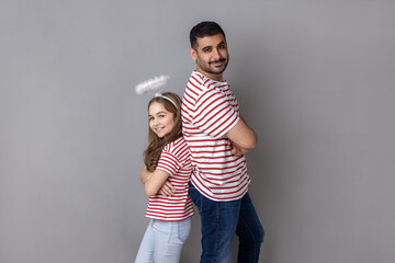 Portrait of lovely father and daughter in striped T-shirts, man and child with halo above head...