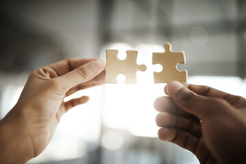 Teamwork, unity and growth with puzzle pieces in the hands of business people building, growing and working together as a team. Closeup of colleagues showing togetherness and synergy from below