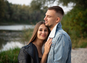 romantic couple sitting on the beach in autumn forest near lake and playing guitar