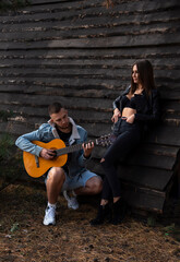 couple playing guitar in the street near wood house