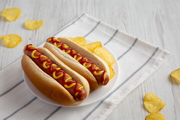 Homemade Hot Dog with Ketchup and Yellow Mustard with Chips on a Plate, side view.
