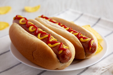 Homemade Hot Dog with Ketchup and Yellow Mustard with Chips on a Plate, side view. Close-up.