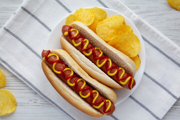 Homemade Hot Dog with Ketchup and Yellow Mustard with Chips on a Plate, top view. Flat lay,...