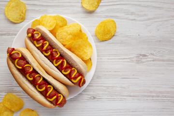 Homemade Hot Dog with Ketchup and Yellow Mustard with Chips on a Plate, top view. Flat lay,...