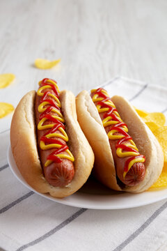 Homemade Hot Dog with Ketchup and Yellow Mustard with Chips on a Plate, side view. Close-up.