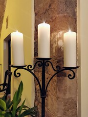 three-armed iron candlestick with three large natural-coloured candles illuminated