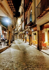 Fototapeta na wymiar medieval village street at night with stone porticoed pavements with columns