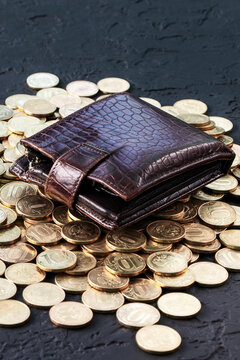 Gold coins and wallet on a black background. Pile of gold coins.Copy space. Treasure Hunt.A Purse with money. Wallet wit gold coins. Vertical orientaion.