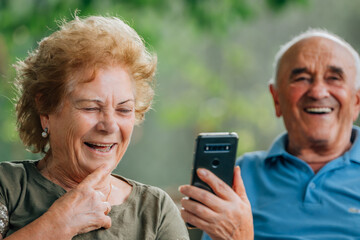 senior couple smiling fun with mobile phone or smartphone