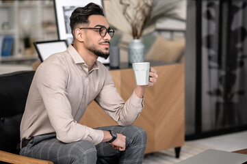 Meditating man with coffee sitting sideways to camera