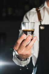 Espresso coffee. coffee glass shot with dark espresso. Barista holds a glass shot with espresso. The trend drinks concept. Vertical photo