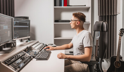 Man working in music studio using computer wearing glasses. Sound engineer working and mixing...