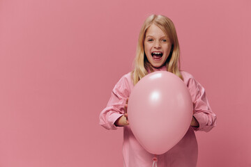horizontal portrait of a girl in a pink shirt on a pink background with a pink balloon in her hands, screaming loudly looking at the camera