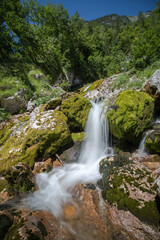 a waterfall between moss-covered boulders at the source of the Soča River