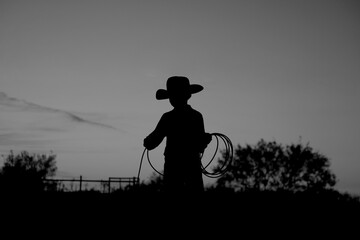 Young cowboy for western silhouette on ranch lifestyle with rope for rodeo industry.