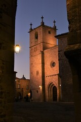 Cáceres, Spain - October 8, 2017: stern stone facade of Cathedral of Santa Maria against a fading clear autumn sky, lit by a few street lanterns from Plaza de San Jorge
