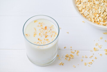 bowl of granola with a spoon and a glass of oat milk. white wooden background. top view. copy space.