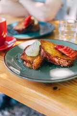 Fototapeta na wymiar French toast with honey syrup, cream and strawberries