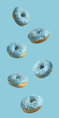 Donuts covered with pale blue icing and sprinkled with pearl sugar beads on a light blue background. Closeup