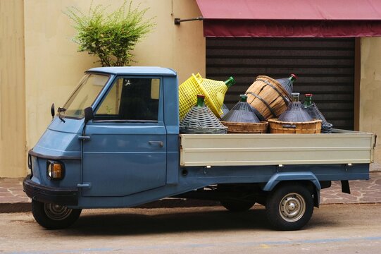Un Ape, motorino italiano a tre ruote, caricato di damigiane per vino contadino, Italia