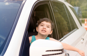 cute baby boy on driver seat with hands head outside expressing hooray ready for trip.kid have fun...