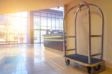 Vintage empty hotel baggage cart in lobby hotel on foreground. Hotel trolley barrow silver chrome...