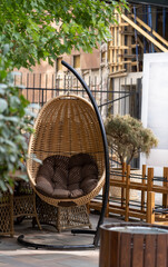 Round hanging chair with brown pillow on outdoor backyard in cafe, relaxing lesure concept. Closeup...
