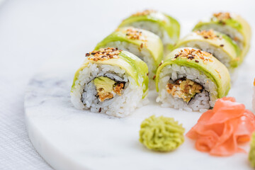 Sushi rolls on platter, bright background. Served with wasabi and ginger. Assorted Japanese sushi. Traditional food. 