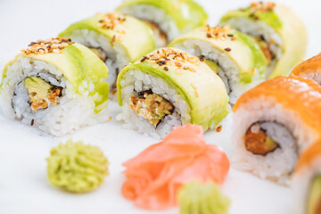Sushi rolls on platter, bright background. Served with wasabi and ginger. Assorted Japanese sushi. Traditional food. 